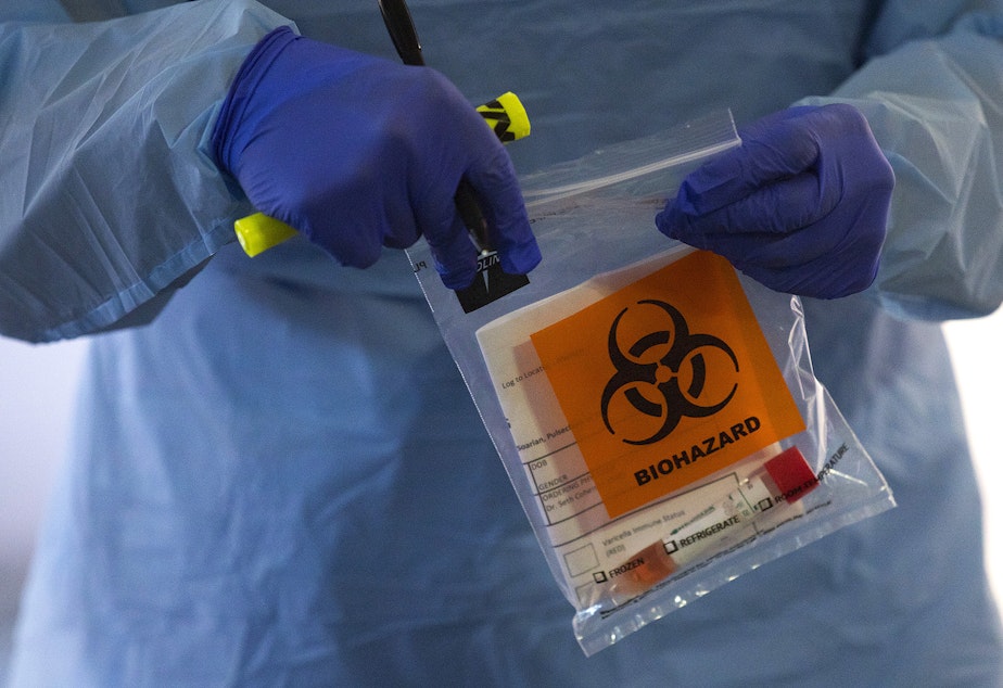caption: A nurse places a coronavirus testing kit into a bag on Thursday, March 12, 2020, at UW Medicine's drive-through testing clinic in Seattle.