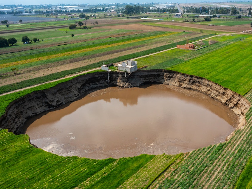 caption: A giant sinkhole in Santa MarÃ­a Zacatepec, Mexico, is almost 500 feet across and has already swallowed the house pictured above since June 9.