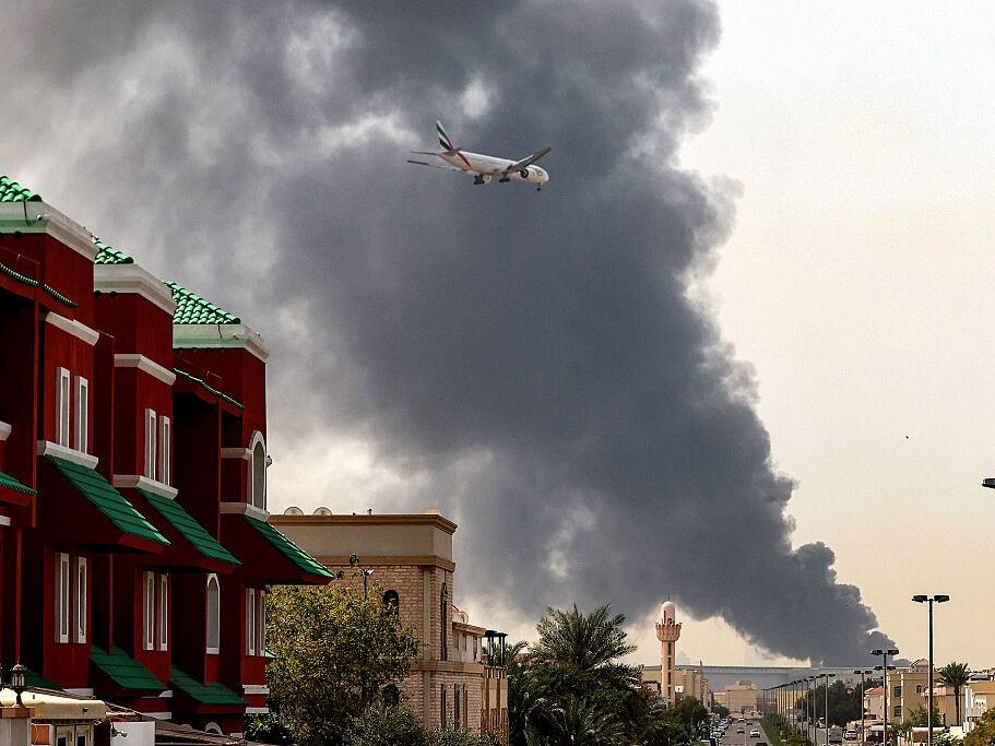 caption: An Emirates aircraft prepares for landing as a smoke plume rises from an ongoing fire near Dubai International Airport in Dubai, United Arab Emirates, on Monday.