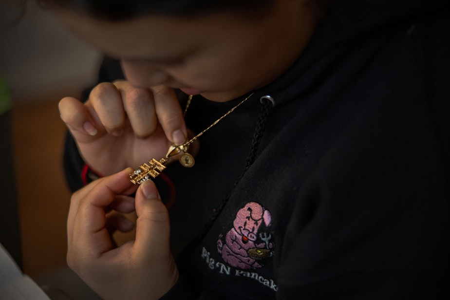 caption: Michelle Aguilar Ramirez looks at a cross called the Caravaca de la Cruz, which she says she wears to bring good fortune and inner peace, at her home in Spokane, Washington.
