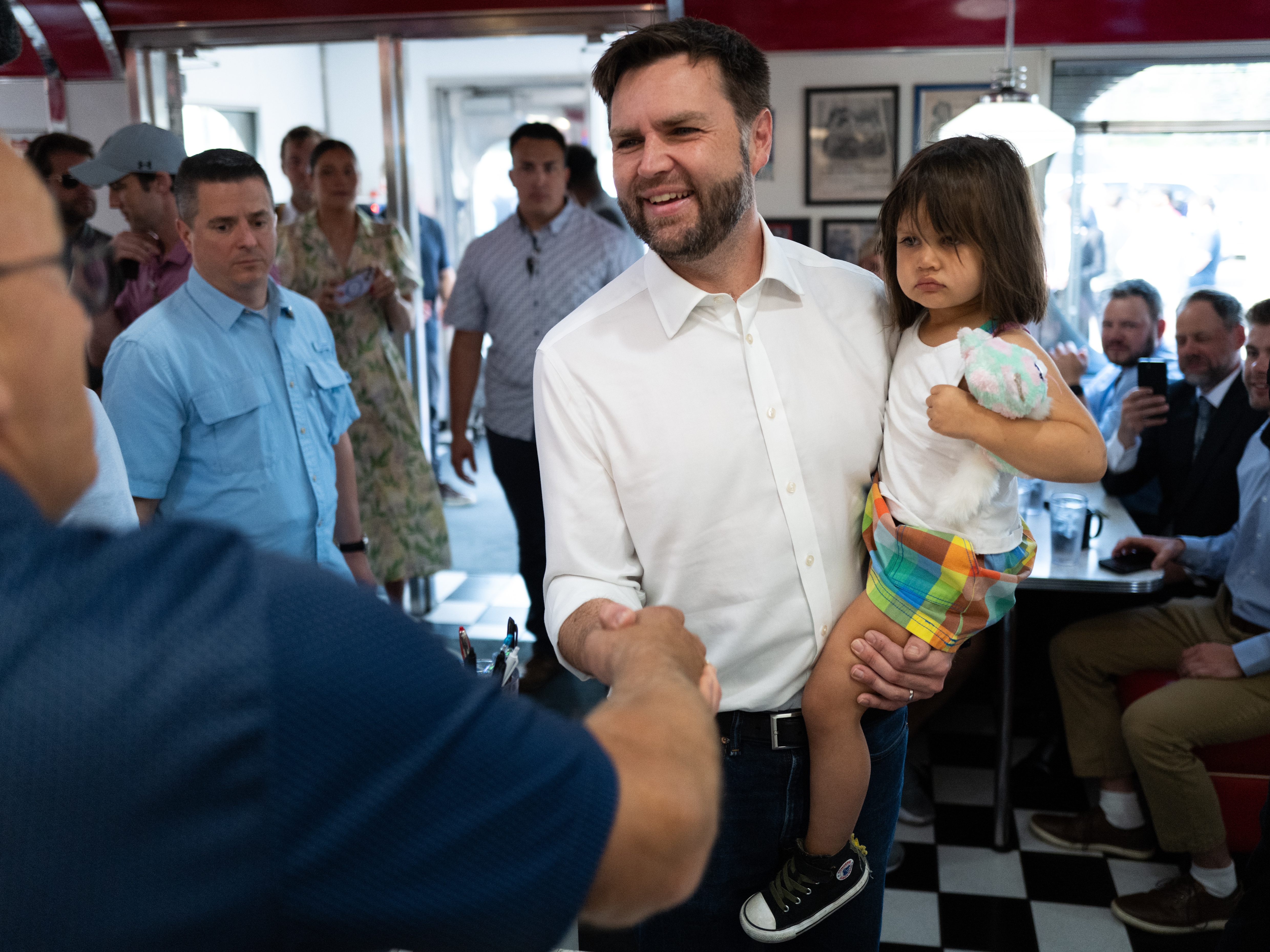 caption: Ohio Sen. JD Vance, the Republican vice presidential nominee, carries his daughter, Maribel, on the campaign trail in St. Cloud, Minnesota. Vance and his wife, Usha, also have a young son, Vivek. 