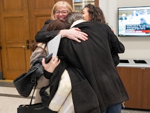 caption: Lisa Sales, President of the Virginia National Organization for Women, embraces her colleagues Federico Cura, of Arlington, Mariam Torosyan, who flew in from Armenia to testify, and Tamar Dekanosidze, of Bethesda, after giving testimony on HB 994 in front of the Senate committee on Courts of Justice on Wednesday, February 28, 2024 at General Assembly Building in Richmond, Virginia.