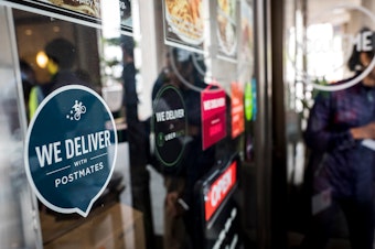 caption: A restaurant in San Francisco displays the logo of Postmates food delivery company.