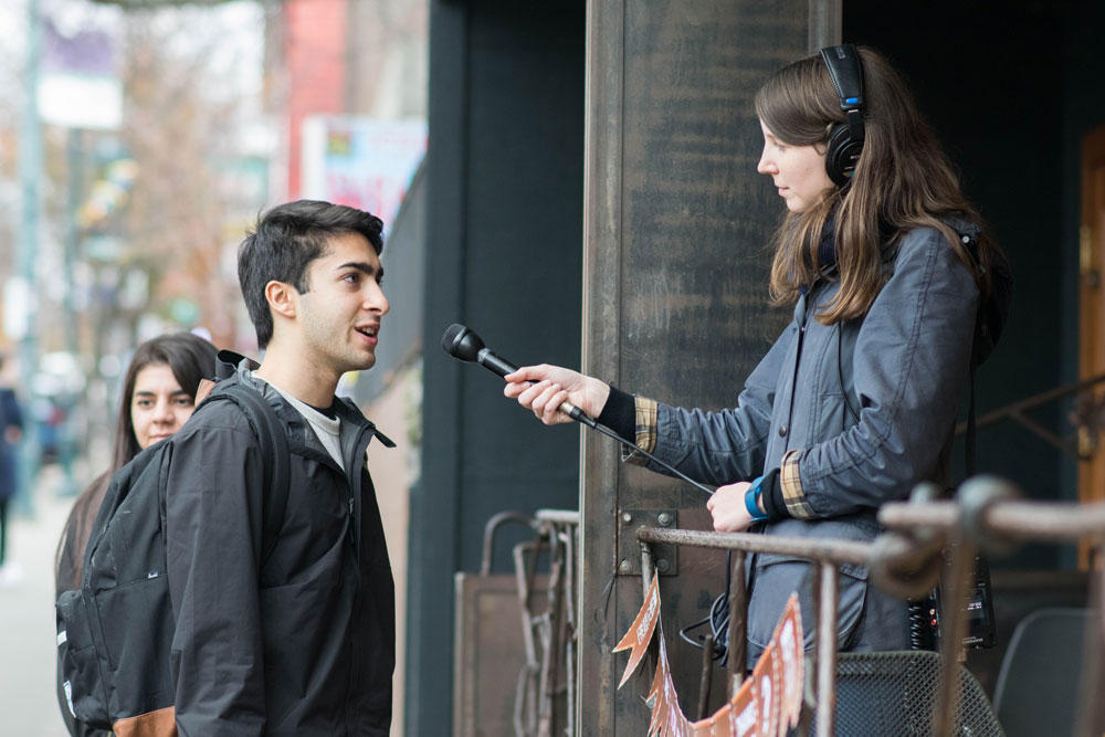 caption: KUOW producer Caroline Chamberlain Gomez interviews a passerby in Seattle's University District.