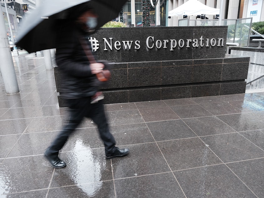caption: People walk past News Corp. headquarters in New York City on Friday. The global media company announced that it  suffered a cyberattack that was discovered last month.