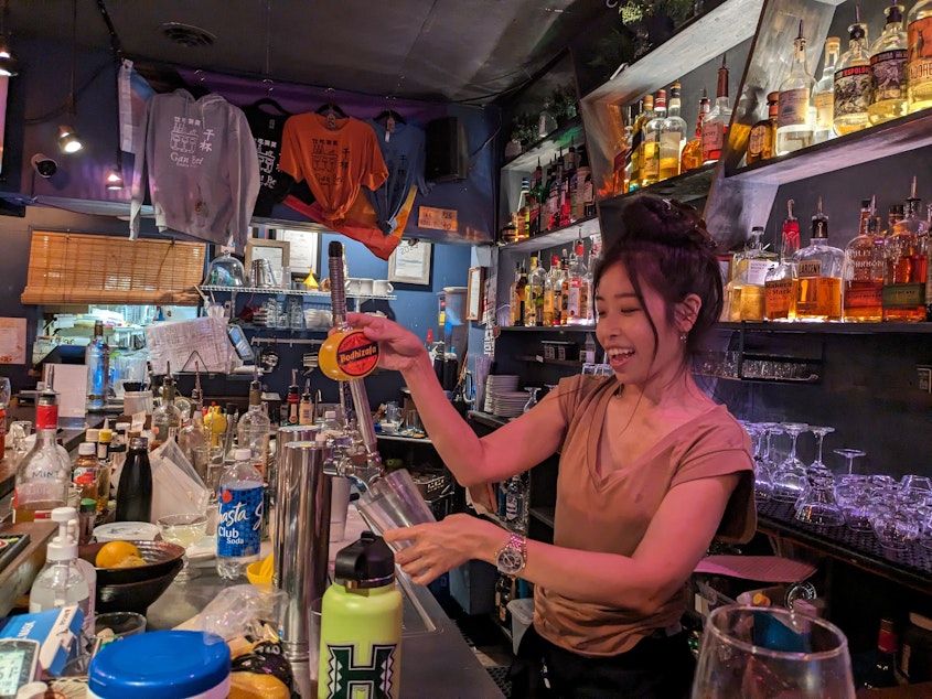caption: Yen Ma pours a beer at the bar inside Gan Bei Eatery and Bar. 