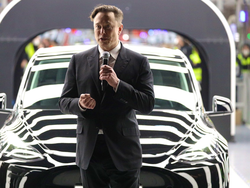 caption: Tesla CEO Elon Musk speaks during the official opening of the new Tesla electric car manufacturing plant on March 22, 2022 near Gruenheide, Germany.