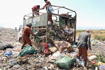 caption: Trash collectors from Marsabit Safi Services offload waste at the Dadach Boshe dump. Even though Kenyan banned single-use plastic bags in 2016, they're still piling up at the dump and blowing off to litter the landscape and bodies of water.