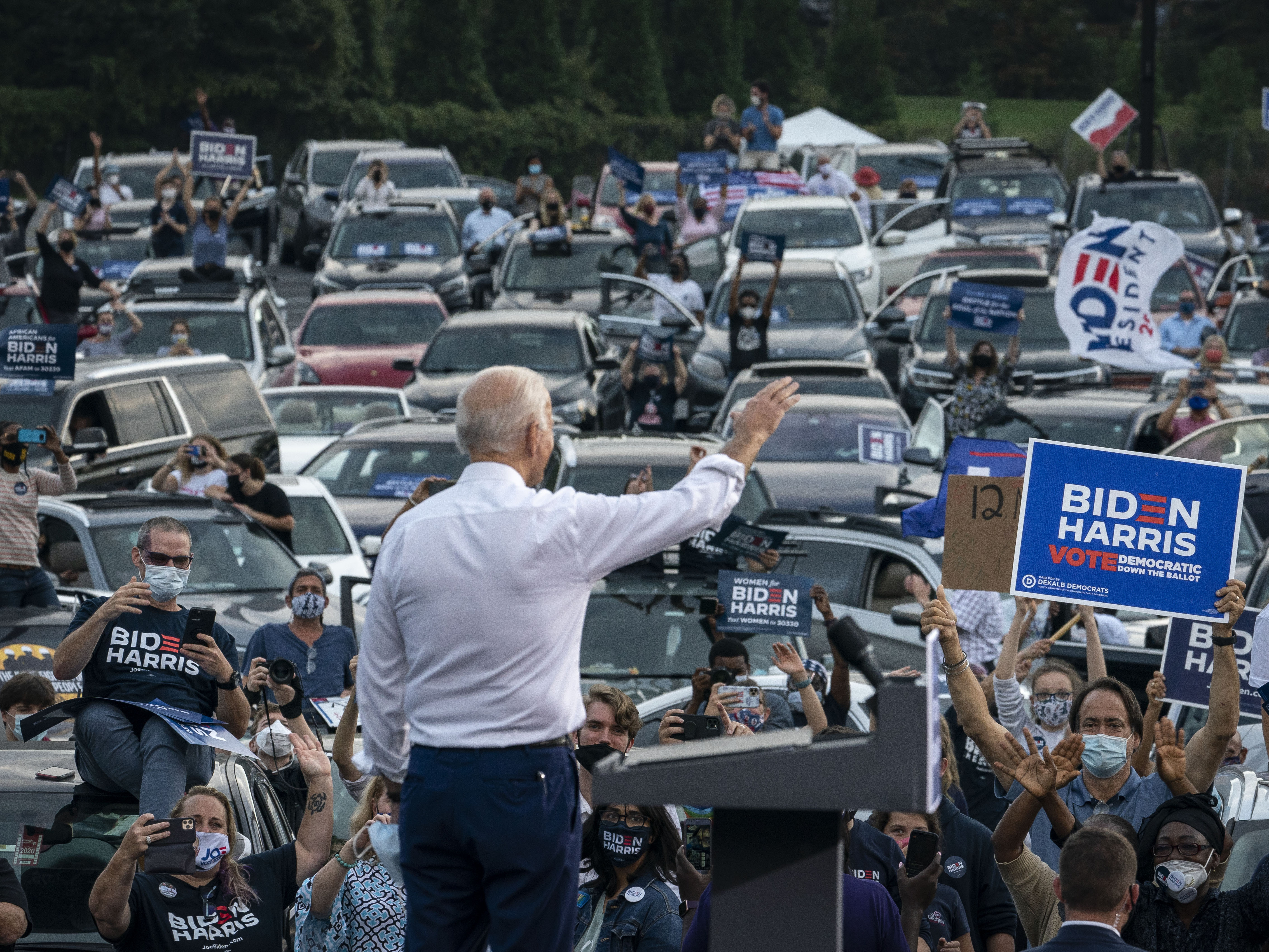 caption: Then presidential candidate Joe Biden waves to supporters as he finishes speaking during a drive-in campaign rally in Georgia in 2020.