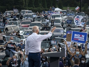 caption: Then presidential candidate Joe Biden waves to supporters as he finishes speaking during a drive-in campaign rally in Georgia in 2020.