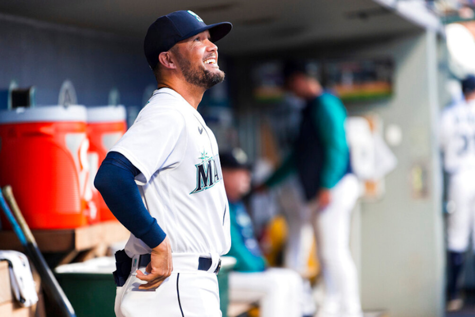 caption: Seattle Mariners first base coach Kristopher Negron smiles in the dugout as the team warms up before a baseball game against the Texas Rangers, Wednesday, Sept. 28, 2022, in Seattle. The Mariners won 3-1. 