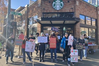 caption: Employees at a Starbucks in Seattle's University District strike on November 17, 2022. The local strike was part of a nationwide demonstration on Starbucks' annual Red Cup Day, when customers who order a holiday drink receive free reusable cups.