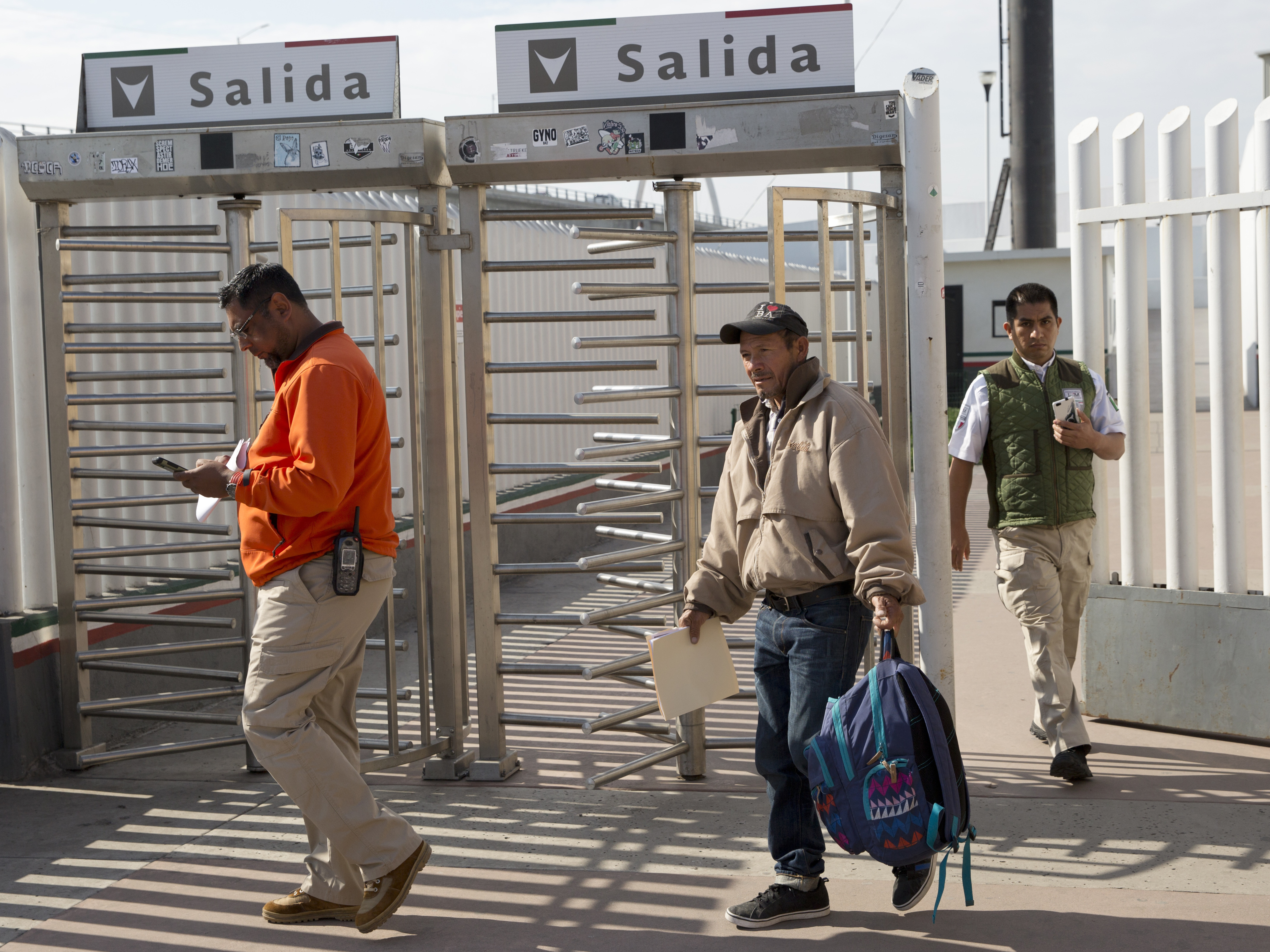 caption: Carlos Catarldo Gomez, of Honduras, center, is escorted by Mexican officials after leaving the United States, the first person returned to Mexico to wait for his asylum trial date, in Tijuana, Mexico