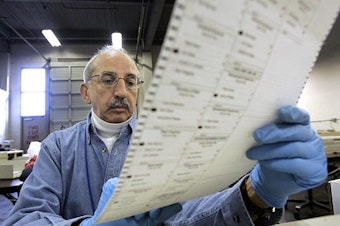 caption: Election worker Ed Faccone looks over a ballot to see why it would not read in a tabulating machine at a King County election tabulating center Wednesday morning, Nov. 17, 2004, in Seattle.