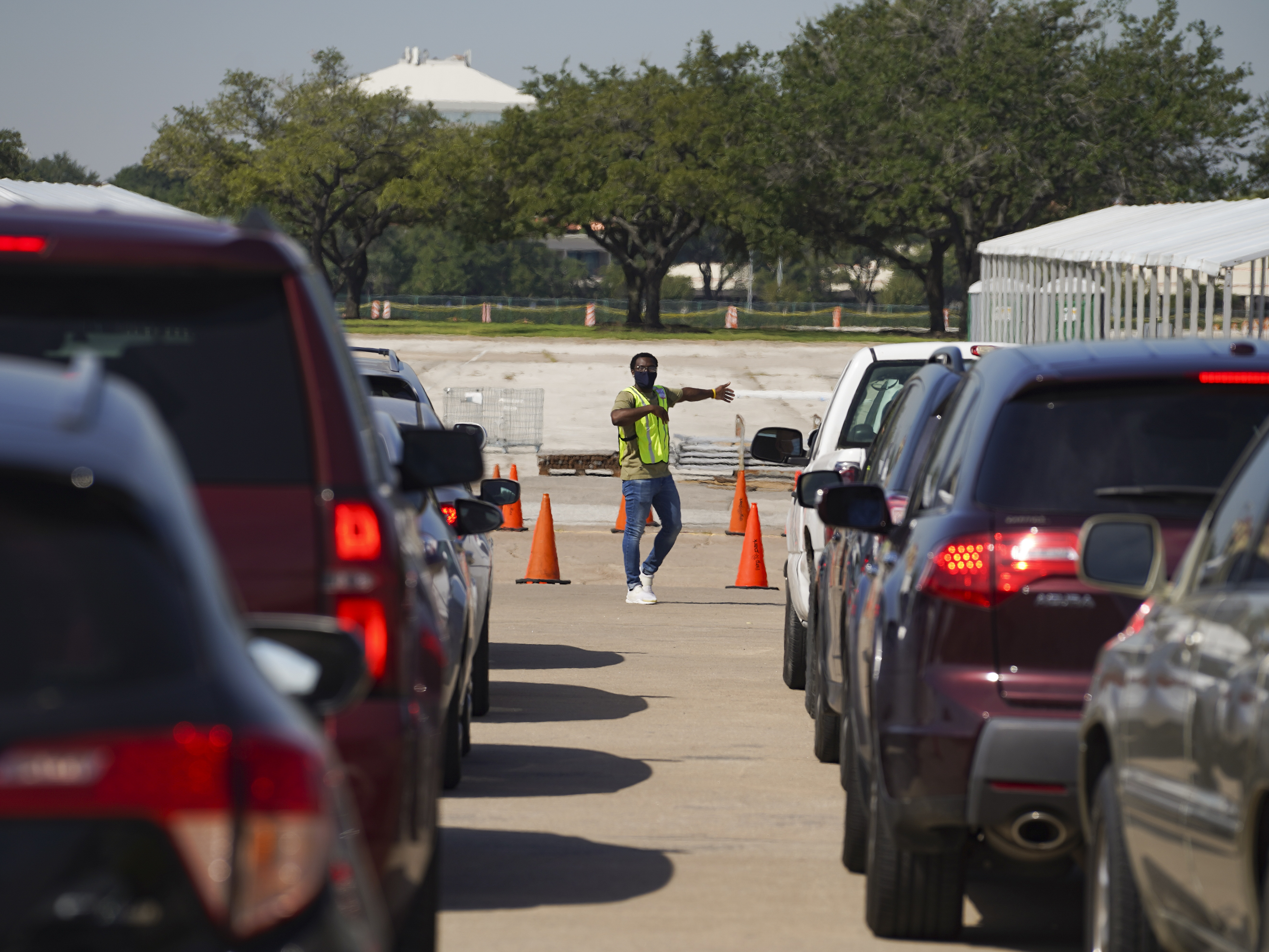 caption: An election worker guides voters in cars at a drive-through voting site in Houston on Oct. 7.