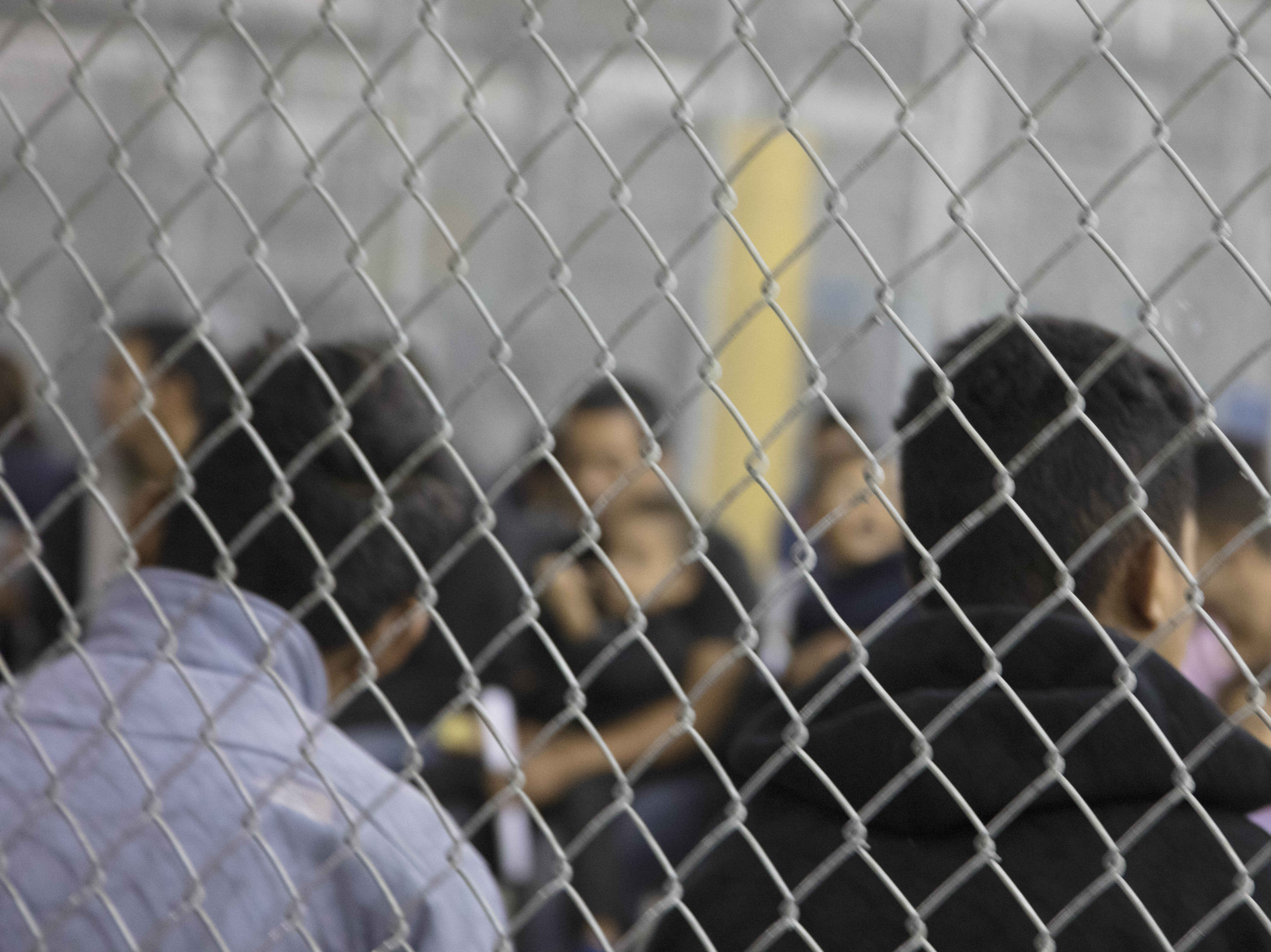 caption: U.S. Border Patrol agents conduct intake of at the Central Processing Center in McAllen, Texas. The center is temporarily closing after the outbreak of "a flu-related illness."