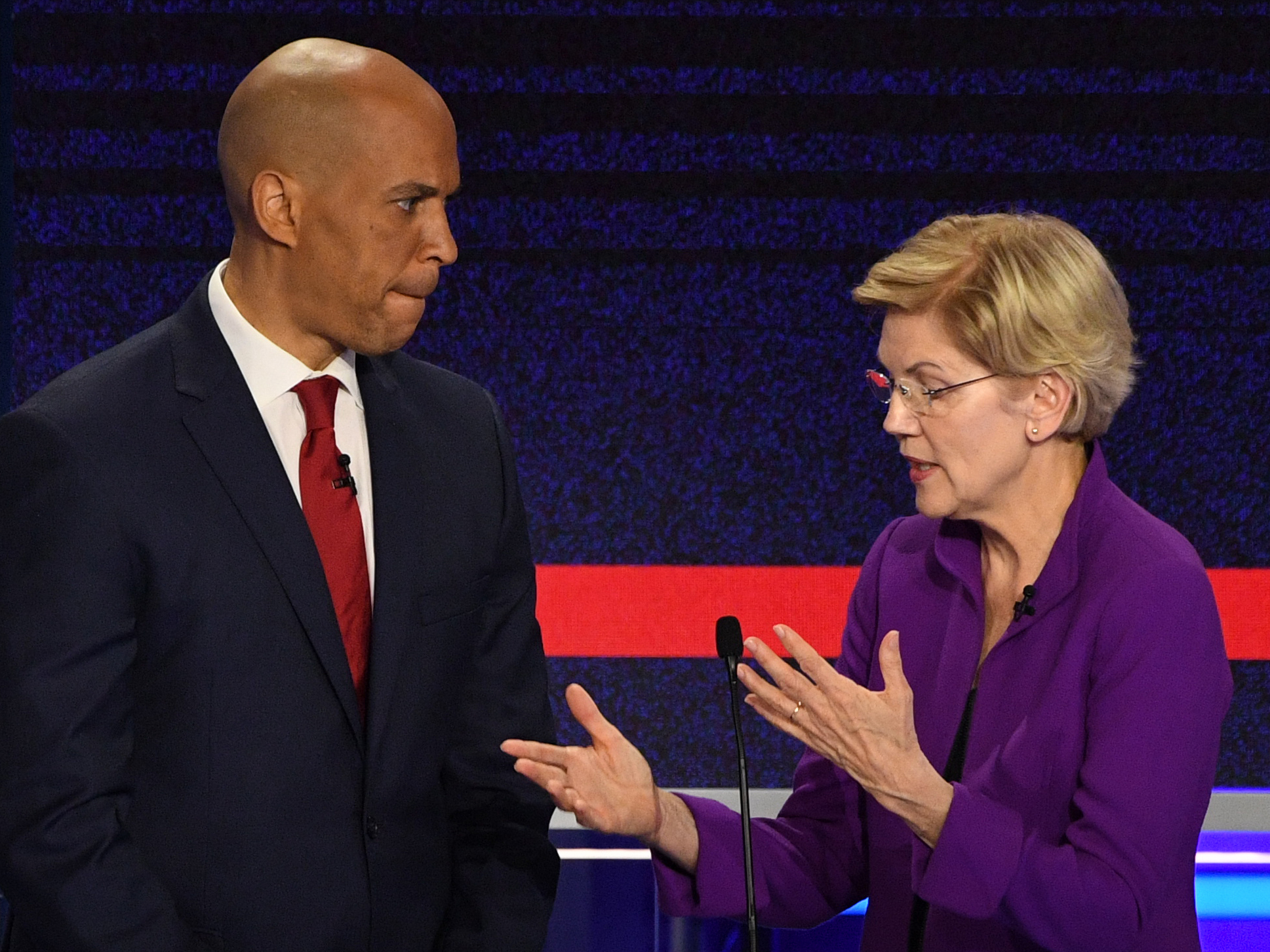 caption: Democratic Sens. Cory Booker and Elizabeth Warren chat during a break in the first Democratic primary debate of the 2020 presidential campaign season. Both announce they had breakthrough COVID-19 infections.
