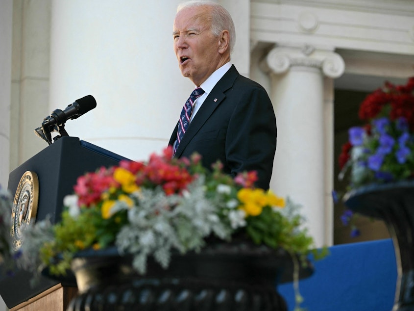caption: President Biden speaks at the Memorial Amphitheater in Arlington National Cemetery during celebrations for Veterans Day on Saturday in Arlington, Virginia.