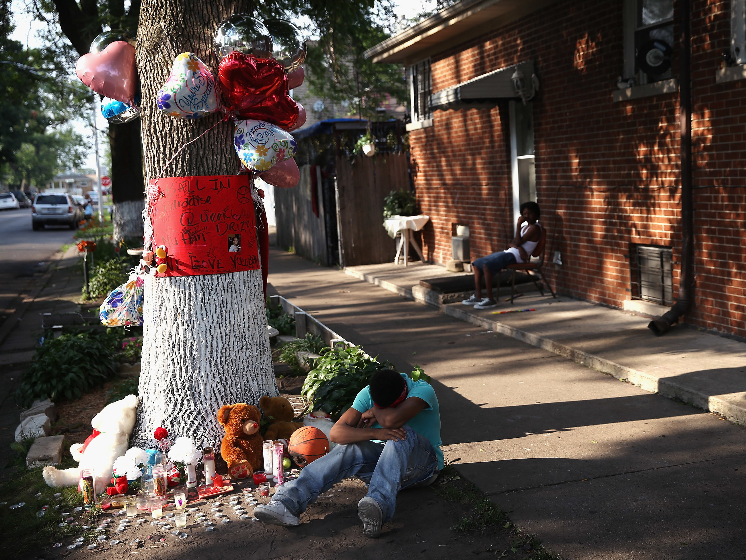 CHICAGO, IL - JULY 06: A teenage boy grieves next to a makeshift memorial at the site where Ashley Hardmon was shot and killed on July 4, 2013 in Chicago, Illinois. (Photo by Scott Olson/Getty Images)