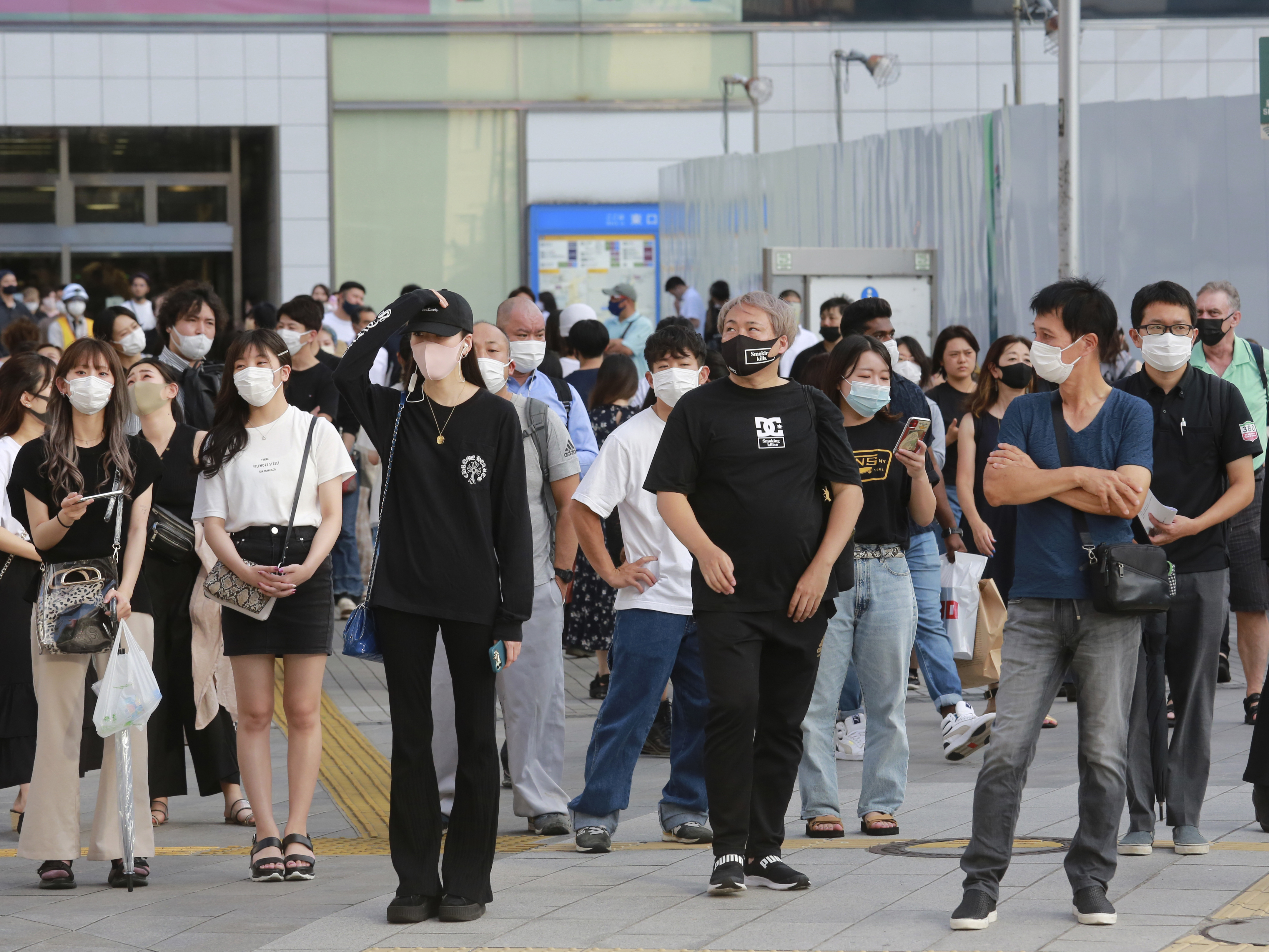caption: People wearing face masks to protect against the spread of the coronavirus stand at an intersection in Tokyo on Tuesday.