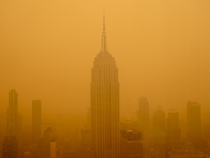 caption: Smoky haze from wildfires in Canada obscures New York City's Empire State Building this year.  The air in the U.S. has improved over the past 50 years, but smoke pollution from growing wildfires erodes much of that progress.