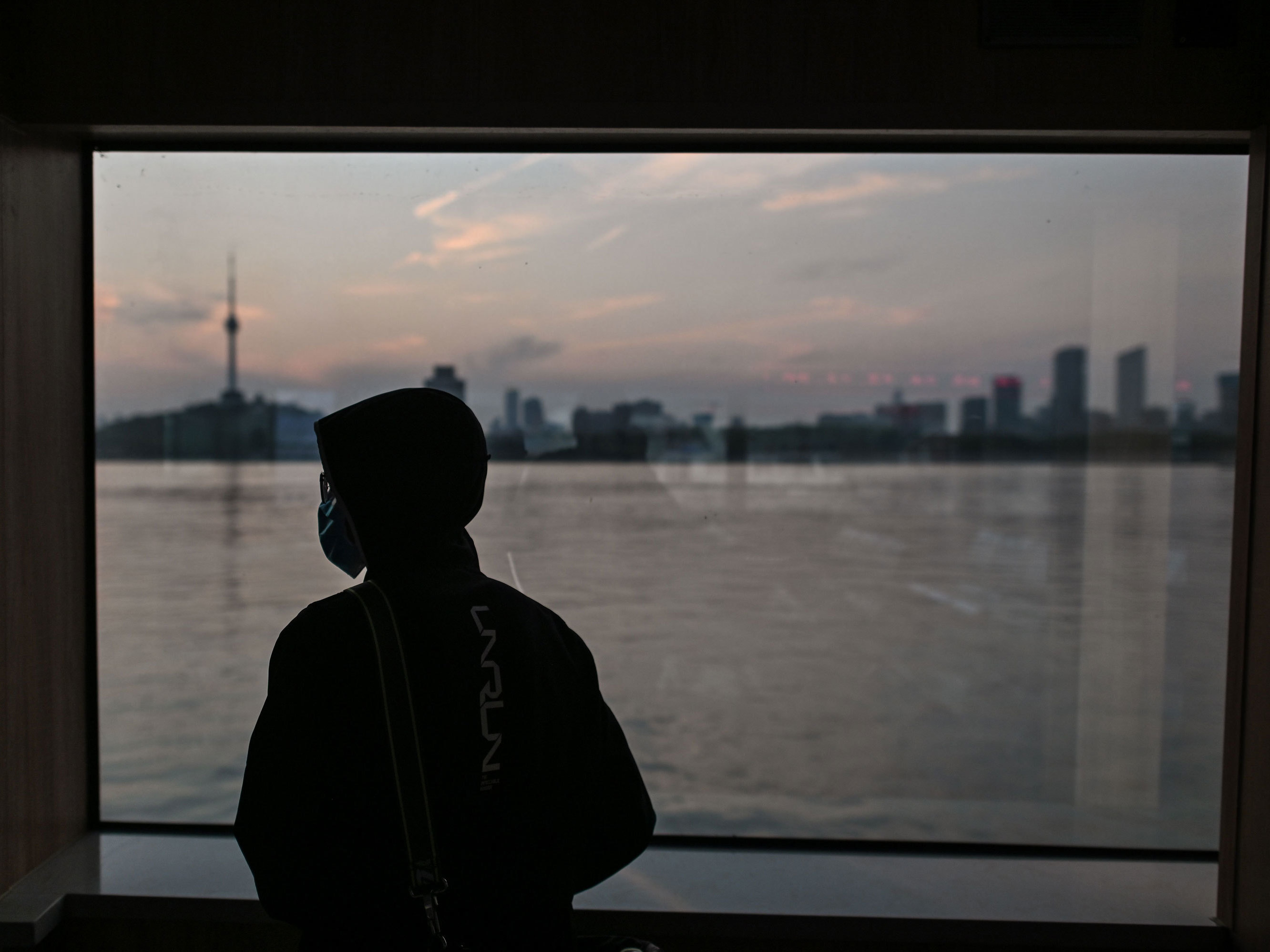 caption: A man wearing a face mask travels on a ferry to cross the Yangtze River in Wuhan in April. Chinese officials are working to silence people suspected of challenging the narrative that authorities in Wuhan and Beijing acted swiftly and efficiently to contain the coronavirus outbreak.