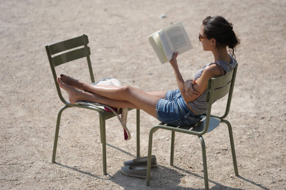 caption: A women reads a book under the sun in the Luxembourg gardens in Paris. (Miguel Medina/AFP via Getty Images)