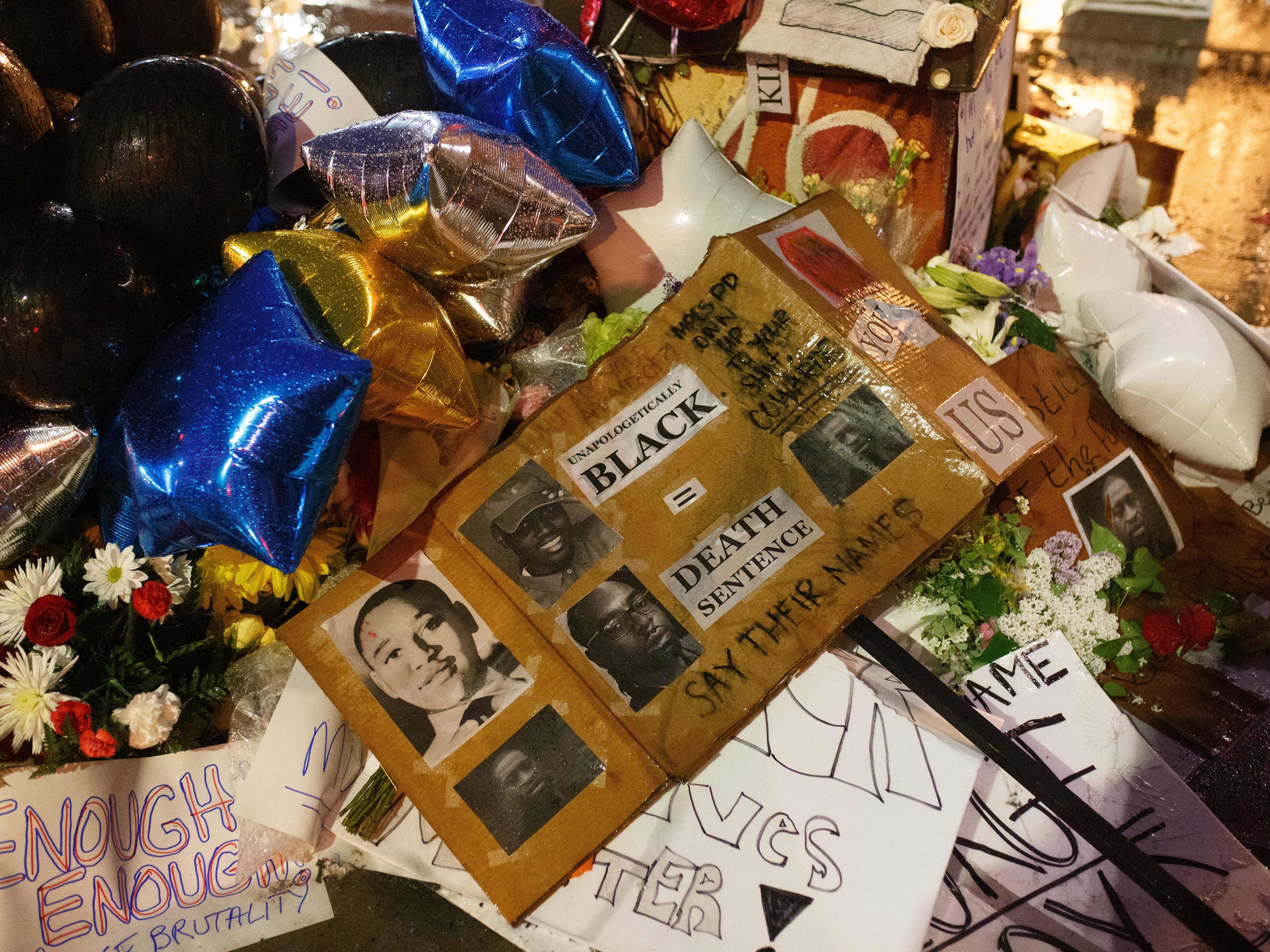 caption: A makeshift memorial, seen Tuesday, has grown near where George Floyd died while in the custody of Minneapolis police. Mourners have brought flowers, signs and balloons to the site in Floyd's memory.