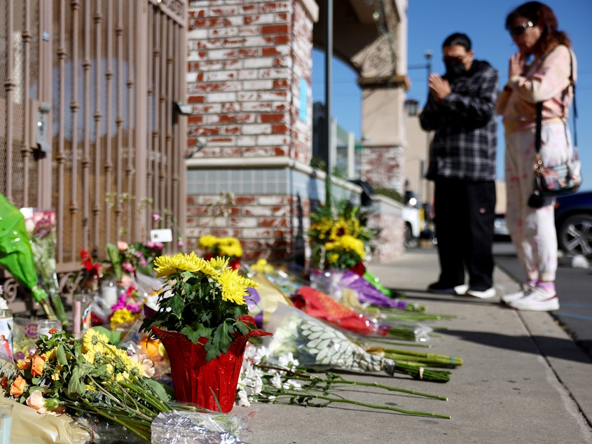 caption: People stand at a makeshift memorial near the scene of the shooting.