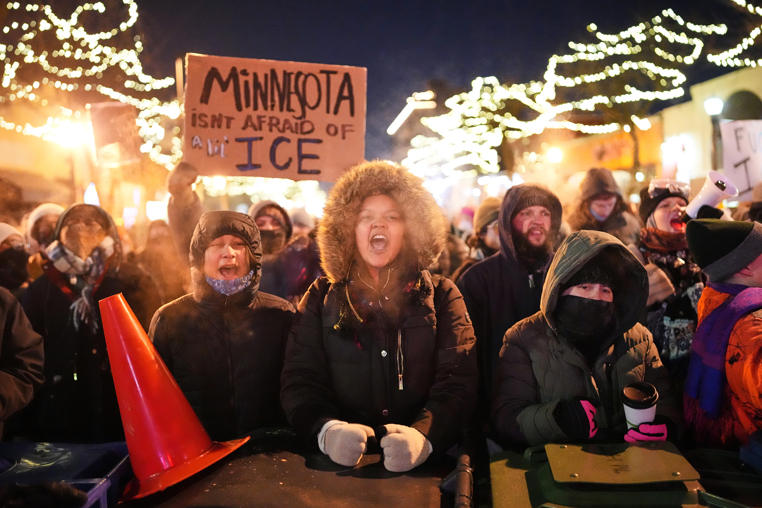 caption: Protesters chant and bang on trash cans as they stand behind a makeshift barricade during a protest in response to the death of 37-year-old Alex Pretti, who was fatally shot by a U.S. Border Patrol officer earlier in the day, Saturday, Jan. 24, 2026, in Minneapolis. 