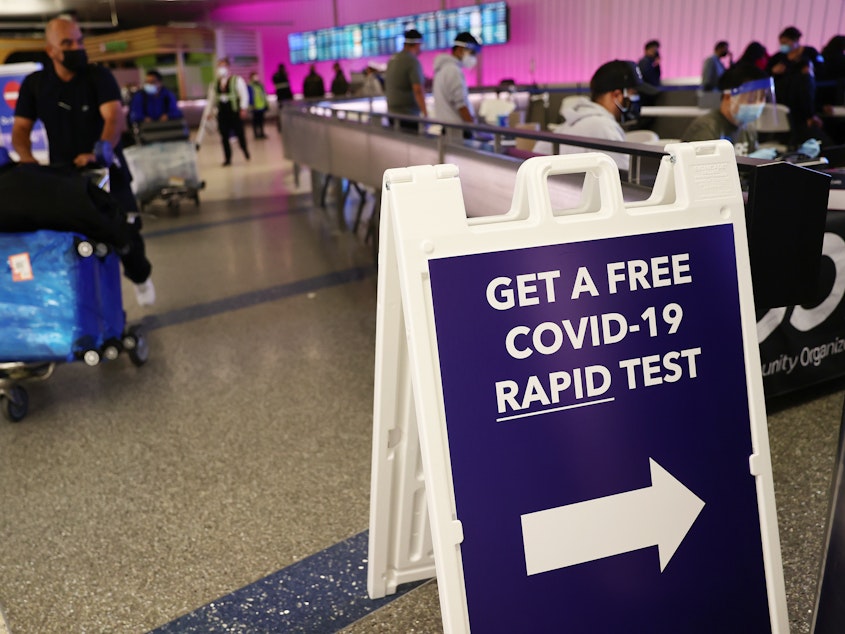caption: An international passenger arrives near a new rapid COVID-19 testing site for arriving international passengers at Los Angeles International Airport (LAX) on Friday in Los Angeles.