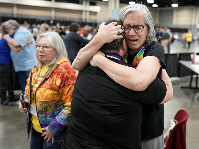 caption: Angie Cox, left, and Joelle Henneman hug after an approval vote at the United Methodist Church General Conference that repealed their church's longstanding ban on LGBTQ clergy and same-sex weddings.