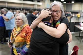 caption: Angie Cox, left, and Joelle Henneman hug after an approval vote at the United Methodist Church General Conference that repealed their church's longstanding ban on LGBTQ clergy and same-sex weddings.