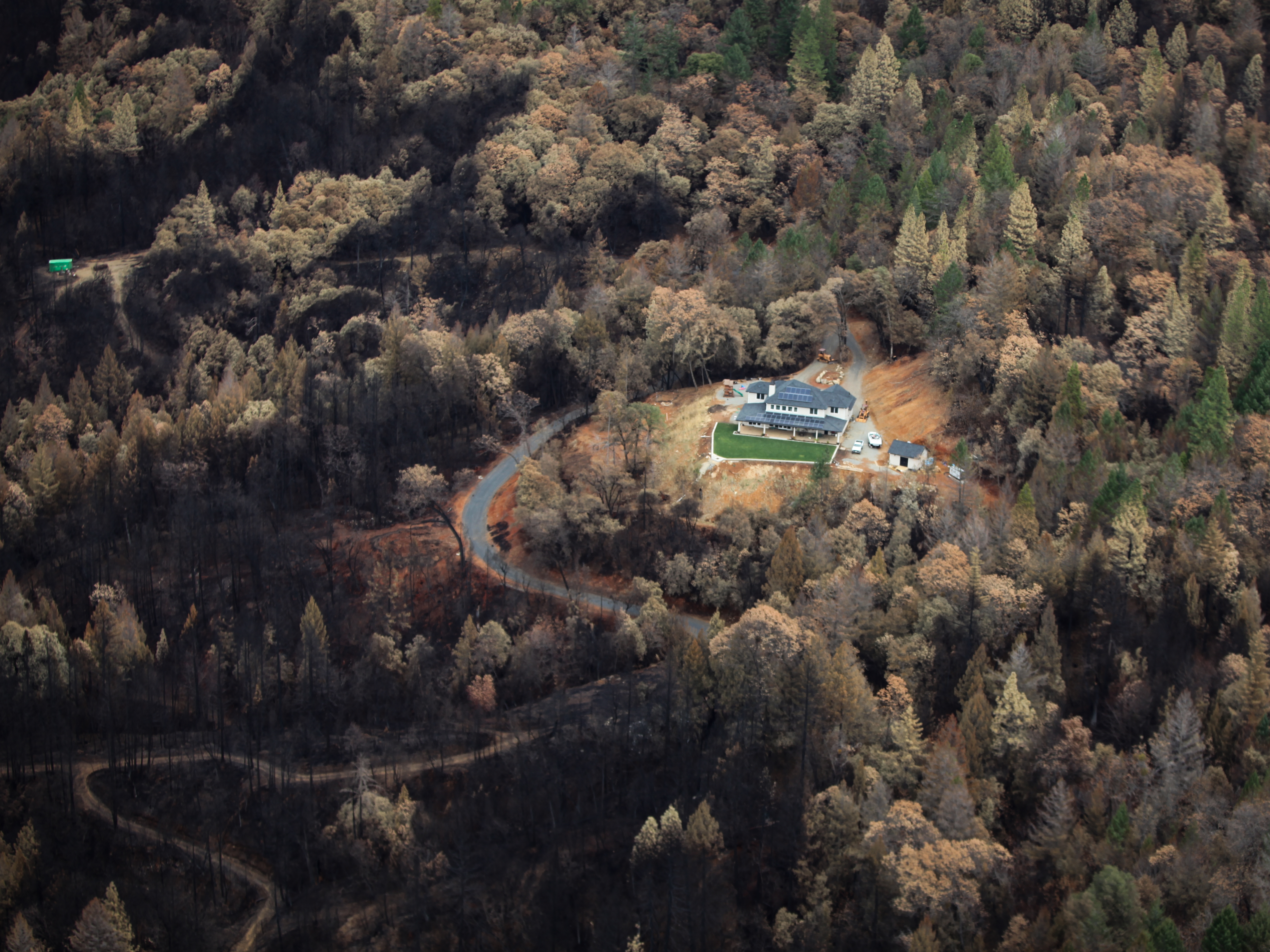 caption: Just outside of Paradise, the charred remains of the Camp Fire stops just short of a home that survived the blaze.