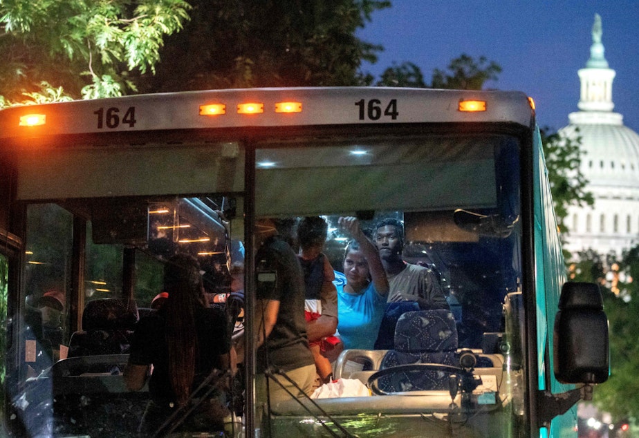 caption: Migrants from Venezuela, who boarded a bus in Del Rio, Texas, disembark within view of the US Capitol in Washington, D.C., on Tuesday.
