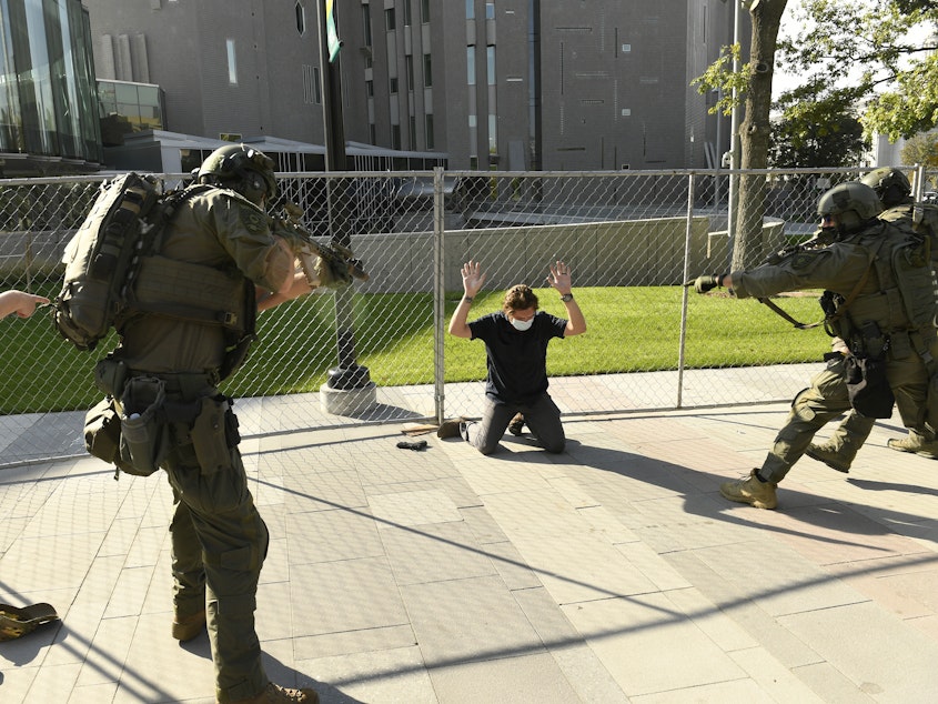 caption: A man holds up his hands as he is taken into custody after a fatal shooting in Denver on Oct. 10. The shooting came at the end of a day of competing rallies by far-right and far-left demonstrators.