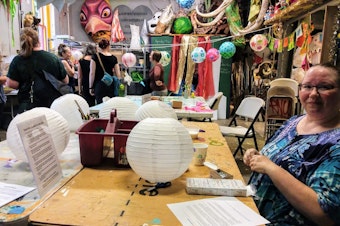 caption: Mimi Noyes, a volunteer instructor, decorates a lantern for the Luminata parade at Green Lake next Thursday.