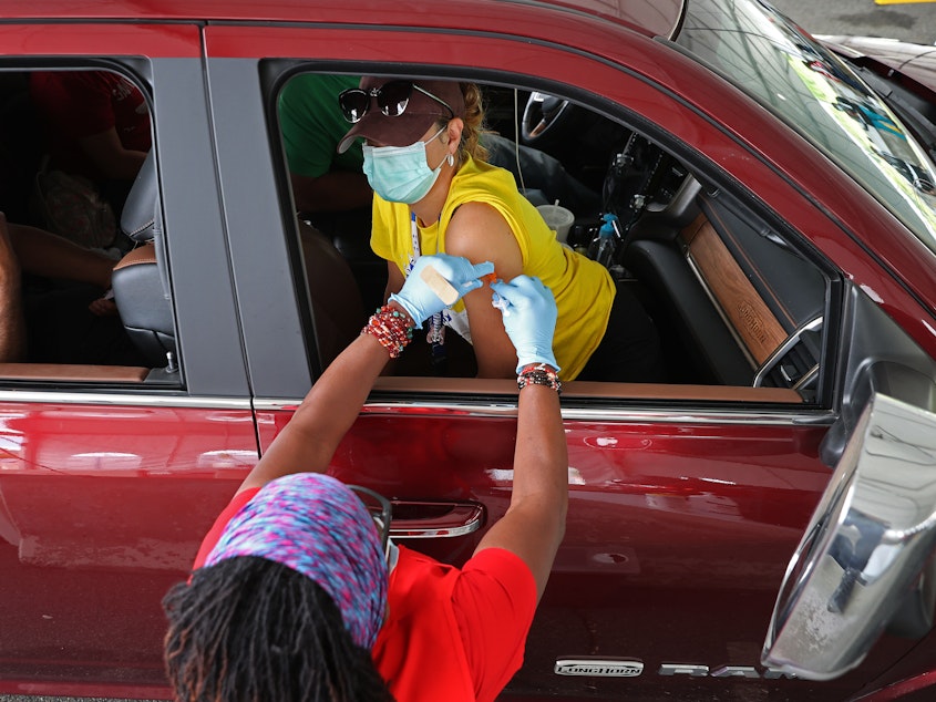 caption: People who need help getting to a vaccination site will be able to get free or discounted rides through Uber and Lyft, the White House says. Here, a woman receives her first dose of the Pfizer vaccine at a mass vaccination site in Aberdeen, Md., after getting a ride to the site from her landlord.
