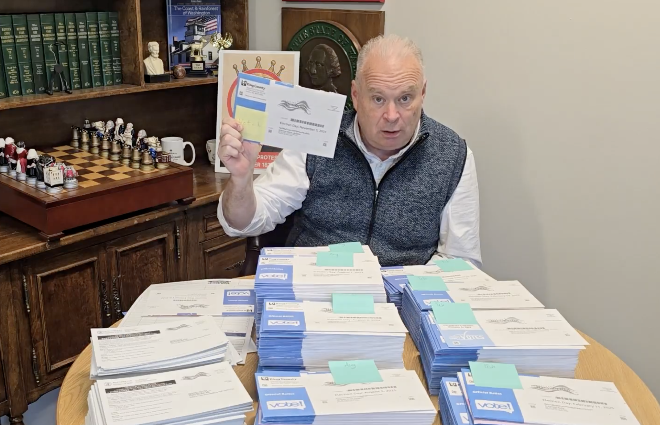 caption: Washington State Republican Party Chair Jim Walsh holds up an unopened ballot, one of 380 found next to a dumpster in Renton. Walsh showed the ballots in a video he posted to social media on April 17, 2026.