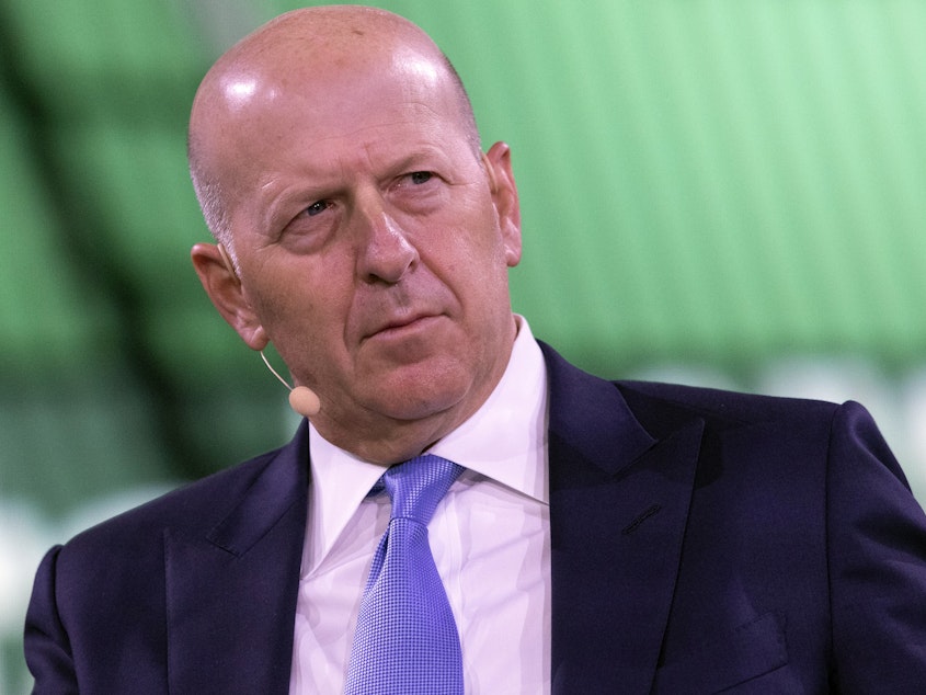 caption: David Solomon, chairman and CEO of Goldman Sachs, shown here at a business roundtable in New York last year, is among several executives at the bank who will have to give back part of their pay.