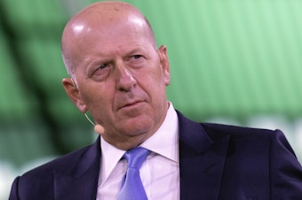 caption: David Solomon, chairman and CEO of Goldman Sachs, shown here at a business roundtable in New York last year, is among several executives at the bank who will have to give back part of their pay.