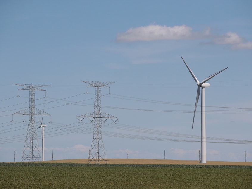 caption: Power lines and power-generating windmills rise above the rural landscape on June 13, 2018, near Dwight, Ill. Driven by falling costs, global spending on renewable energy sources like wind and solar is now outpacing investment in electricity from fossil fuels and nuclear power.