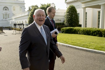 caption: Agriculture Secretary Sonny Perdue will lay out the details of an aid program to help farmers hurt by the ongoing U.S.-China trade dispute on Thursday. Here, Perdue walks past the West Wing of the White House.