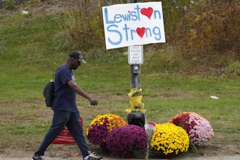 caption: A man walks by flowers and a sign of support for the community, Oct. 28, 2023, in the wake of the mass shootings that occurred on in Lewiston, Maine. The Maine Legislature on Thursday approved sweeping gun safety legislation nearly six months after the deadliest shooting in state history.