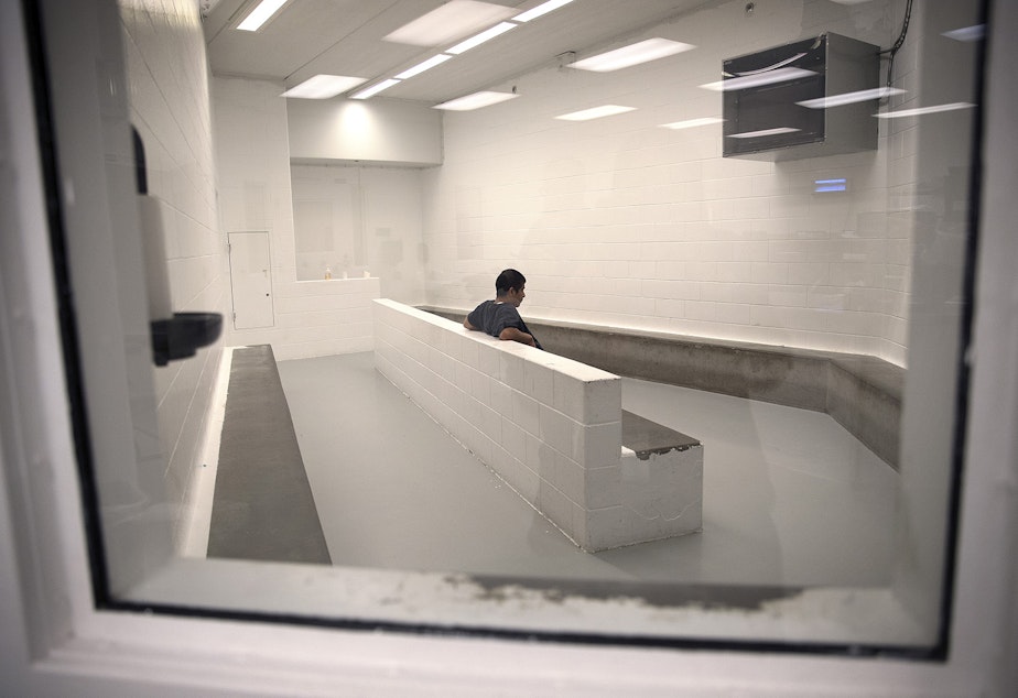 caption: A detainee sits in the intake area at the Tacoma Detention Center in 2017.