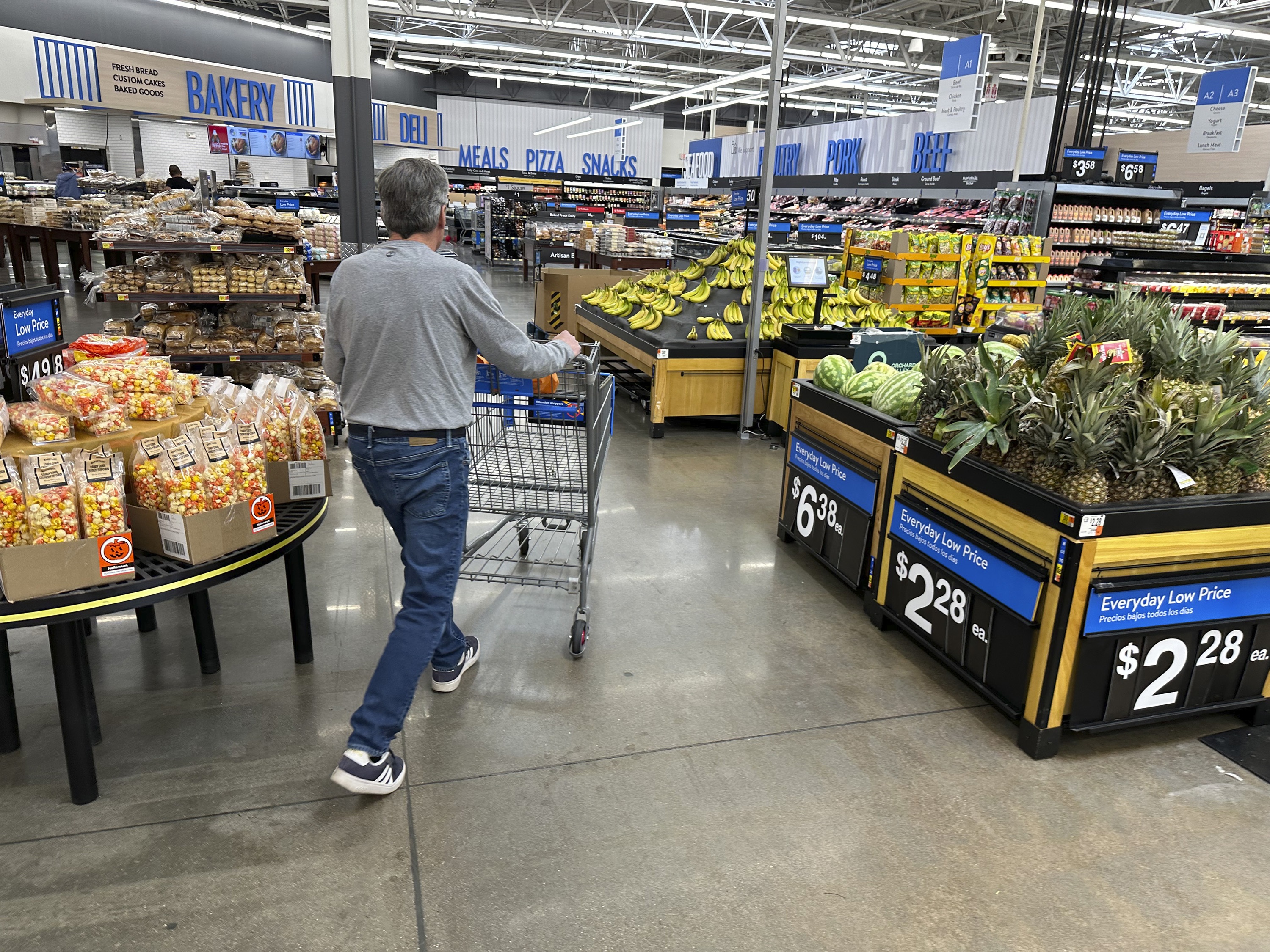 caption: Shopper pushes a basket into the produce section of a Walmart store in Englewood, Colo.