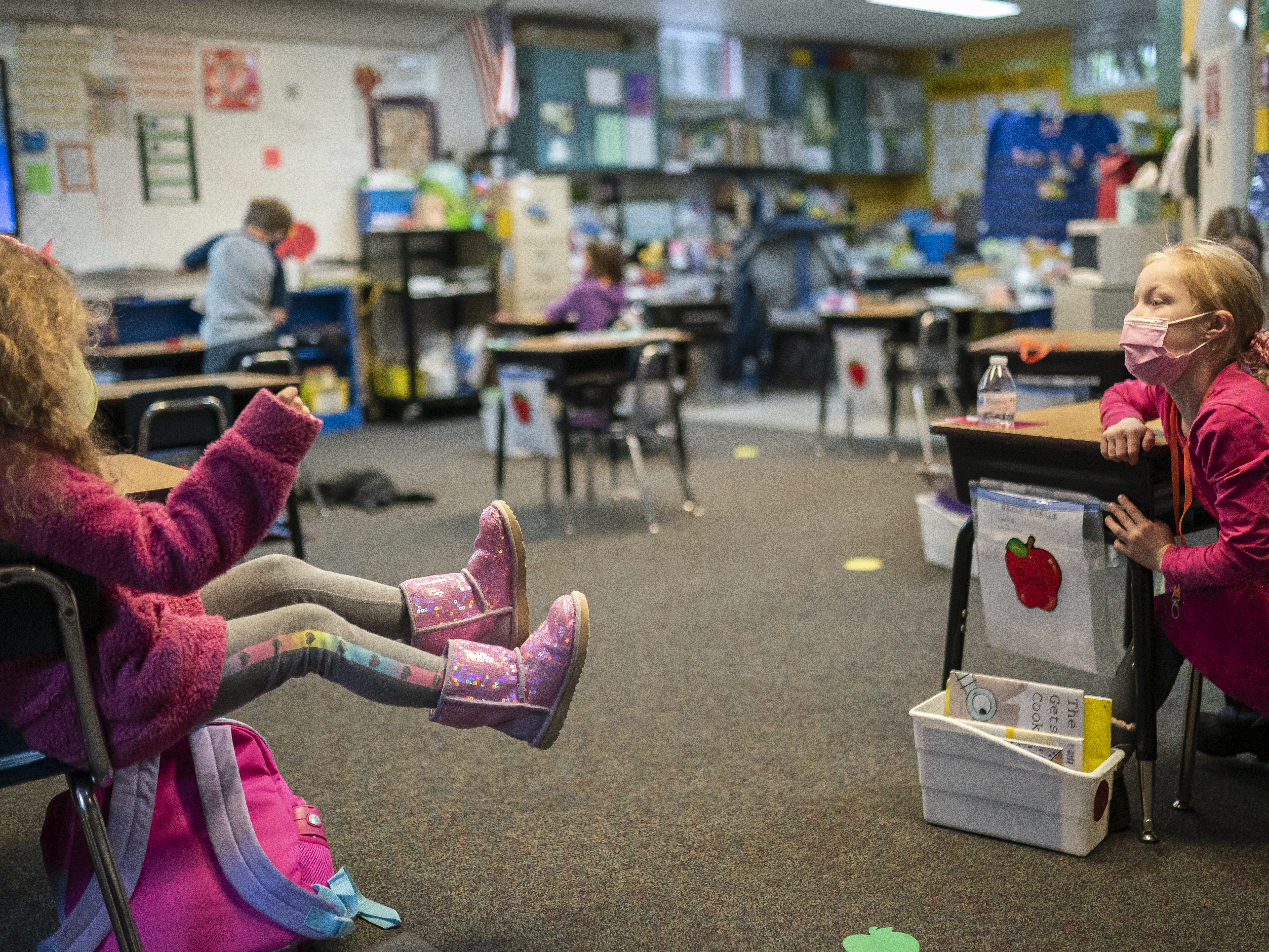 caption: Two first grade students talk in the back of class at the Green Mountain School last month in Woodland, Wash. The CDC's current guidance for schools recommends seating or desks be "at least 6 feet apart when feasible."