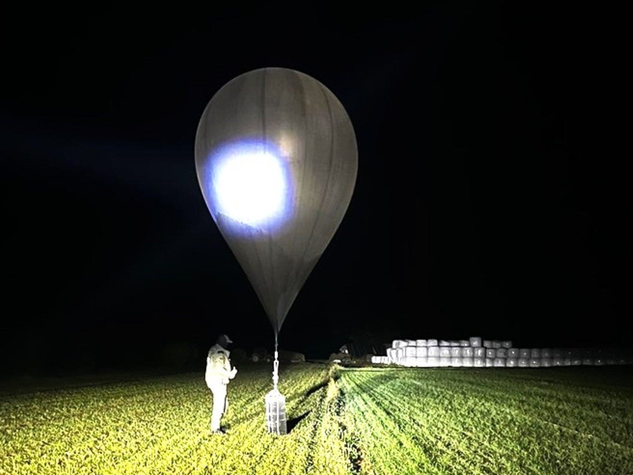 caption: FILE - In this undated photo released by the State Border Guard Service, an officer inspects a balloon used to carry cigarettes into Lithuania, because Belarussian smugglers often use them to ferry the contraband into the European Union.