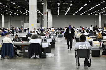 caption: Ballot counters process absentee ballots on Nov. 8 at Huntington Place in Detroit. The scene this year was much calmer than 2020, when protesters descended on Detroit and yelled for election officials to "stop the count!"