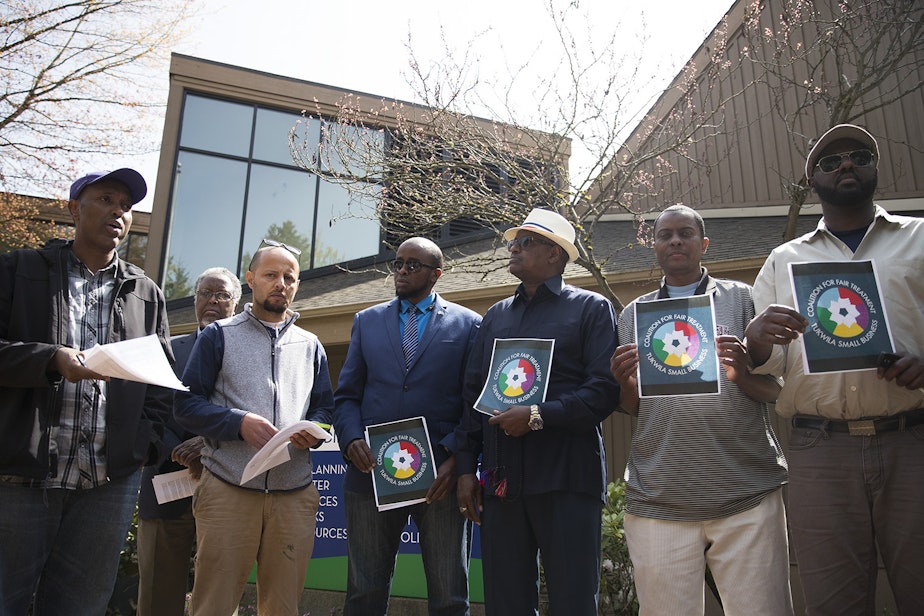 caption: From left, Abdi Adan and Tawfik Maudah and other supporters/business owners read over the  demands that they will make before entering Tukwila City Hall with community members and business owners on Thursday, April 19, 2018, in Tukwila. 